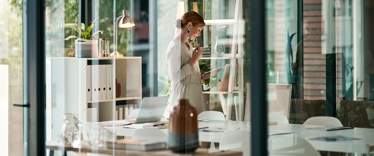 Frau arbeitet im Büro hinter Glas – diskrete und fokussierte Analyse von Vermögensstrategien